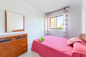 a bedroom with a pink bed with a dresser and a mirror at Apartamento Calle Ciruelo in Aguadulce +17 photos