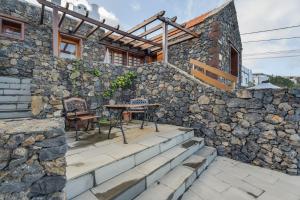 a stone house with a table and chairs on a stone wall at El Almendro in Tesbabo
