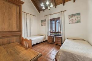 a bedroom with two beds and a table and a window at El Almendro in Tesbabo