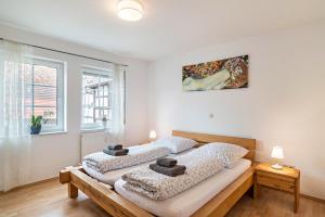 Zwei Betten in einem weißen Zimmer mit einem Gemälde an der Wand in der Unterkunft Aposto Apartments 2 in Oberderdingen