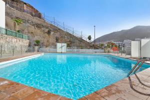 a large blue swimming pool with a chair next to it at Suite Deluxe Puerto Rico 11 in Puerto Rico de Gran Canaria