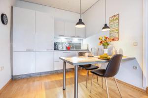 a kitchen with white cabinets and a wooden table and chairs at Alter Laden in Nienstädt +9 photos