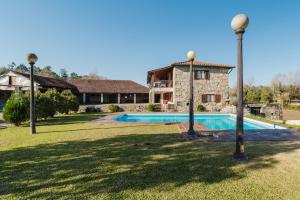 a villa with a swimming pool in front of a house at Quinta Das Regadas in Rendufe
