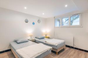 two beds in a white room with a window at Maison Familliale Centre Fromentine in La Barre-de-Monts