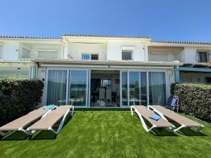 a house with two lounge chairs on the lawn at Beach House El Saladillo in Estepona