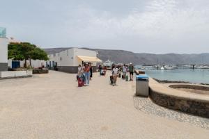 a group of people walking on a sidewalk next to the water at La Caletilla La Graciosa in Caleta de Sebo