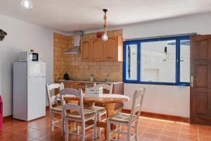 a kitchen with a table and chairs and a refrigerator at La Caletilla La Graciosa in Caleta de Sebo