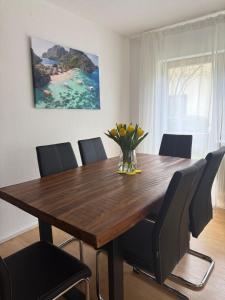 a dining room table with chairs and a vase of flowers at Casa Laguna in Oberteuringen