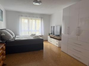 a white bedroom with a bed and a television at Casa Laguna in Oberteuringen