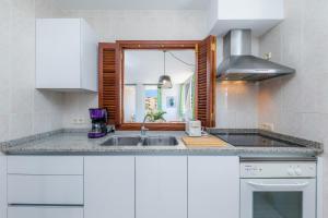 a kitchen with white cabinets and a sink at Apartamento Grillo in Cala Ratjada +16 photos