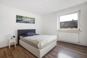 a white bedroom with a bed and a window at Allgäu Space in Marktoberdorf