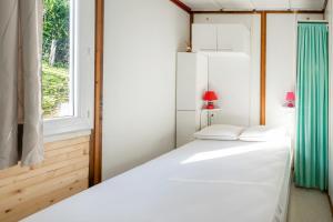 a white bed in a room with a window at Petite maison Ortalon - Hasparren in Hasparren