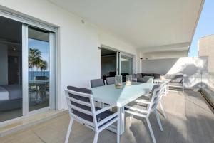 a white dining room table and chairs on a balcony at Modern frontline beach - Estepona in Estepona
