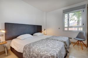 a bedroom with a bed and a window and a chair at Modern frontline beach - Estepona in Estepona +17 photos