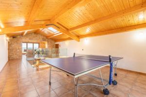 a ping pong table in a room with wooden ceilings at El Puig De Fonollet in Puigreig