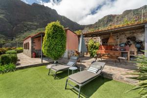 a garden with chairs and an umbrella and a table at Casa La Bobadilla in Agulo