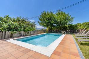 a swimming pool in a yard with chairs and trees at El Puig De Fonollet in Puigreig