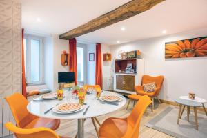a dining room with a white table and orange chairs at Les Glycines 1 in Les Épesses