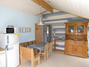 a kitchen with a dining table and a refrigerator at Les Hirondelles du Cap in Plévenon