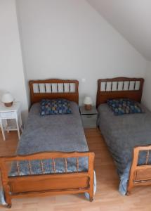 two beds in a room with two tables at Gîte Le Guerichet in Betton