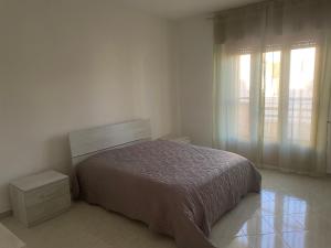 a white bedroom with a bed and a window at Massimo Holiday house in Acquarica del Capo