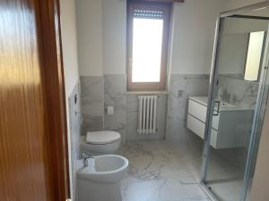 a white bathroom with a toilet and a sink at Massimo Holiday house in Acquarica del Capo