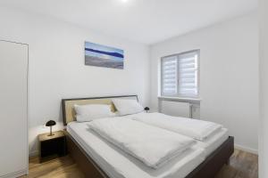 a white bedroom with a bed and a window at Fewo am Mühlenbach in Wehr