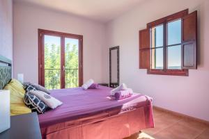 a bedroom with a large purple bed with a window at Finca Son Puca in Petra +18 photos