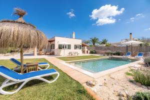 a yard with a pool and chairs and an umbrella at Las Estrellas Cala Llombards in Cala Llombards