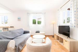 a living room with a couch and a tv at Las Estrellas Cala Llombards in Cala Llombards