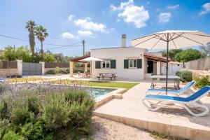 a patio with a chair and an umbrella next to a house at Las Estrellas Cala Llombards in Cala Llombards