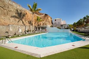 a swimming pool with chairs and a rock wall at Zen House in Puerto Rico de Gran Canaria