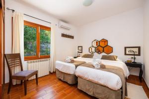 a bedroom with two beds and a chair and a window at Es Puig de Ses Coves in Santa Eugenia +37 photos