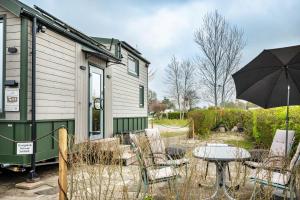 a table with an umbrella in front of a trailer at Tiny House Ingo John 'Speedy' in Sandstedt