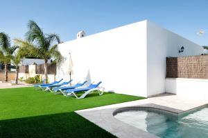 a group of chairs sitting on a lawn next to a pool at Villa Montenmedio - Carmelo in El Soto