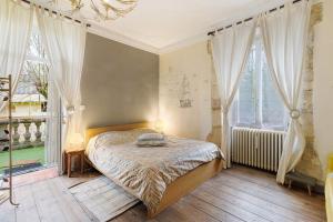 a bedroom with a bed and two large windows at La Belle Gabarre in Groléjac