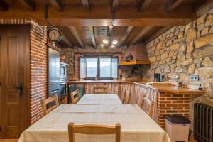 a kitchen with a long table and a brick wall at El Paraiso del Yayo in Ramales de la Victoria