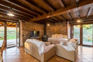 a bedroom with a bed and a tv and some chairs at El Paraiso del Yayo in Ramales de la Victoria