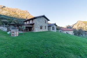 a stone house on a hill with a green field at El Paraiso del Yayo in Ramales de la Victoria