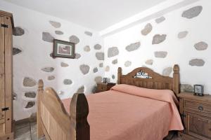 a bedroom with a bed and a rock wall at Vivienda Vacacional Risco Blanco in San Bartolomé +21 photos