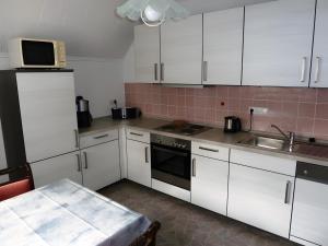a kitchen with white cabinets and a sink and a microwave at Angelas Ferienwohnung in Cuxhaven