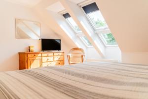 a bedroom with a bed and a tv and windows at Haus Seeblick in Langballig