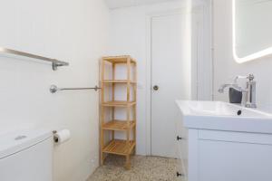 a white bathroom with a sink and a shelf at Moli Apartment Beach in Canet de Mar +20 photos