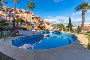 a swimming pool with palm trees and a building at Topacio A114 in Mijas Costa