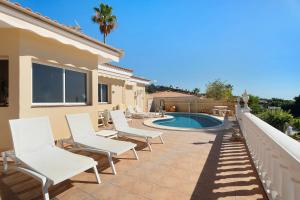 a patio with white chairs and a swimming pool at House Carla Private Pool Heated in Puerto de Santiago