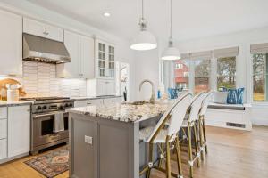 a kitchen with white cabinets and a island with bar chairs at 3 Mins to York Beach Large Deck Water View in York +35 photos