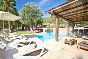 an image of a pool with lounge chairs and an umbrella at Villa Can Rafal Ibiza in Sant Josep de sa Talaia