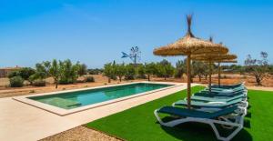 a group of chairs and umbrellas next to a swimming pool at Villa Hort de Can Rafalet in Ses Salines