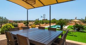 a wooden table with chairs and an umbrella at Villa Hort de Can Rafalet in Ses Salines +8 photos