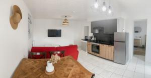 a kitchen and living room with a table and red chairs at Gîte bord de mer - le Chardon in Pirou +15 photos